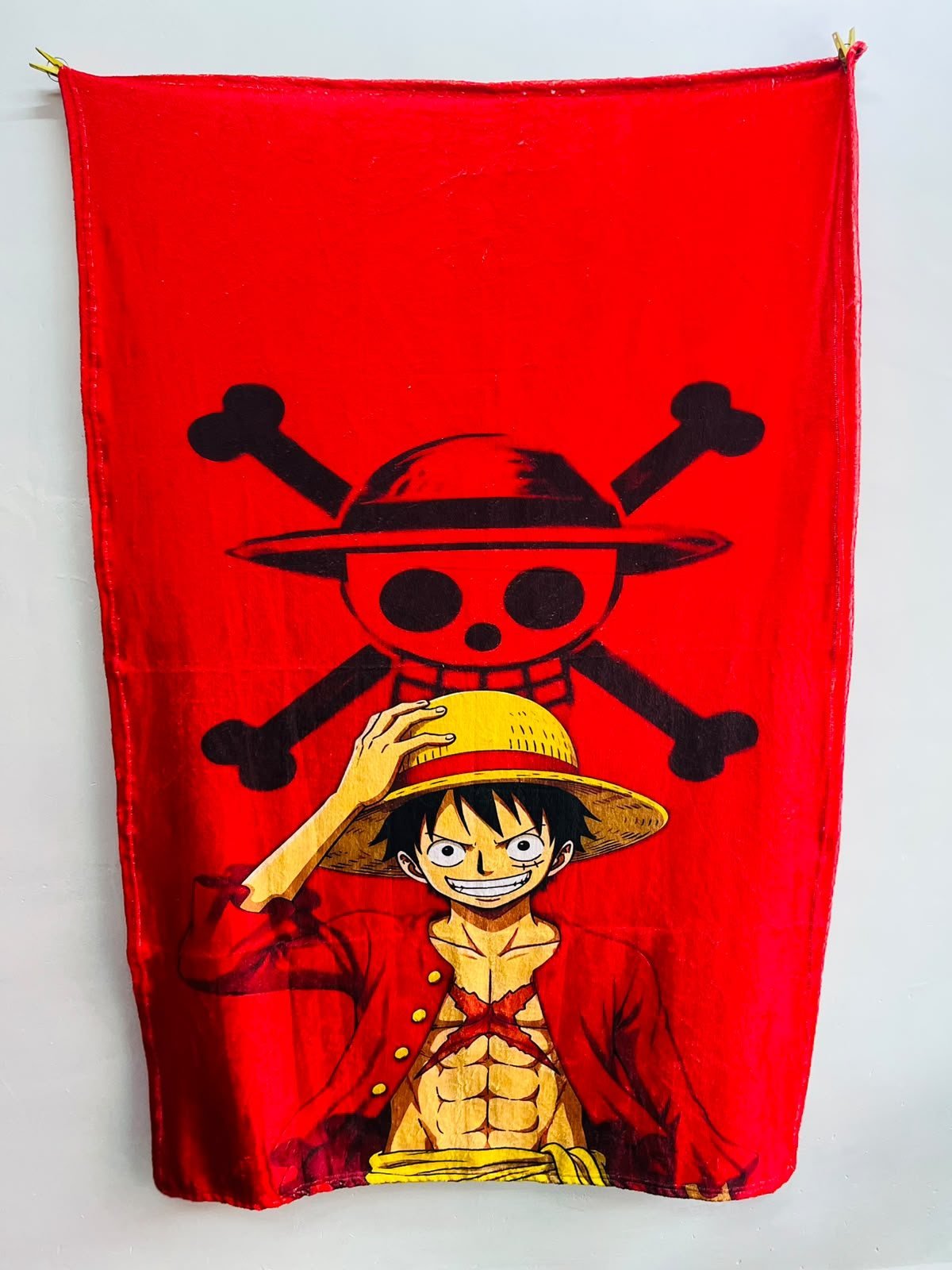 Frazada viajera anime: Luffy de One Piece con su sombrero de paja y la bandera pirata sobre fondo rojo — foto de la frazada real