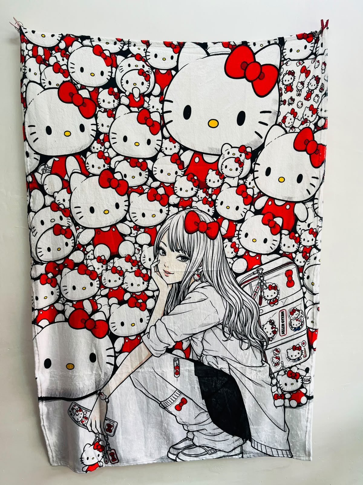 Frazada viajera de Hello Kitty: chica ilustrada en blanco y negro con un fondo lleno de Hello Kittys de moño rojo — foto de la frazada real
